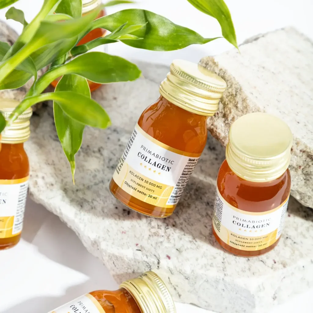 Buteleczki kolagenu Primabiotic ustawione na tle kamienia i zielonych roślin.