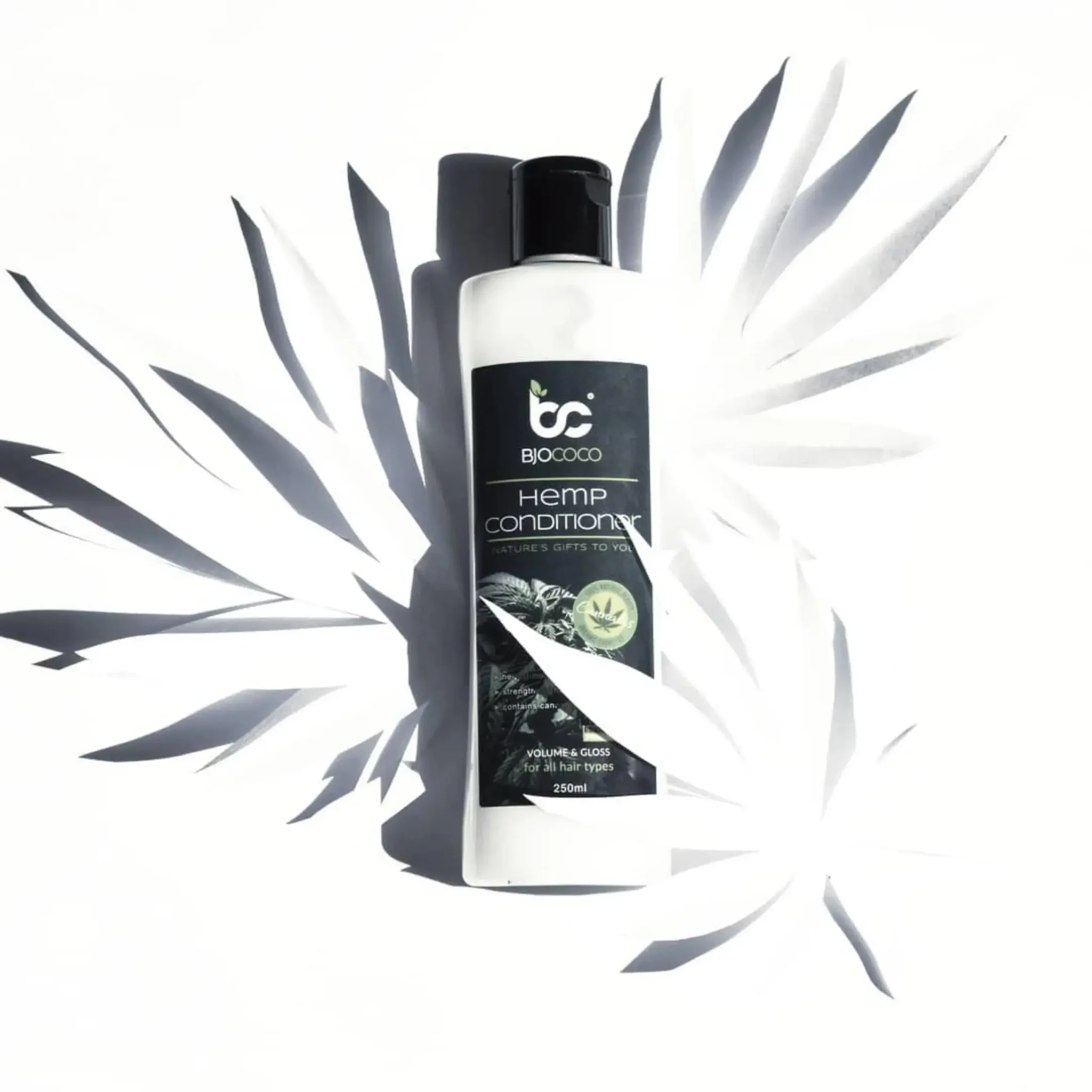 Biały butelka odżywki konopnej BjoCoco z efektem świetlnych liści na białym tle.