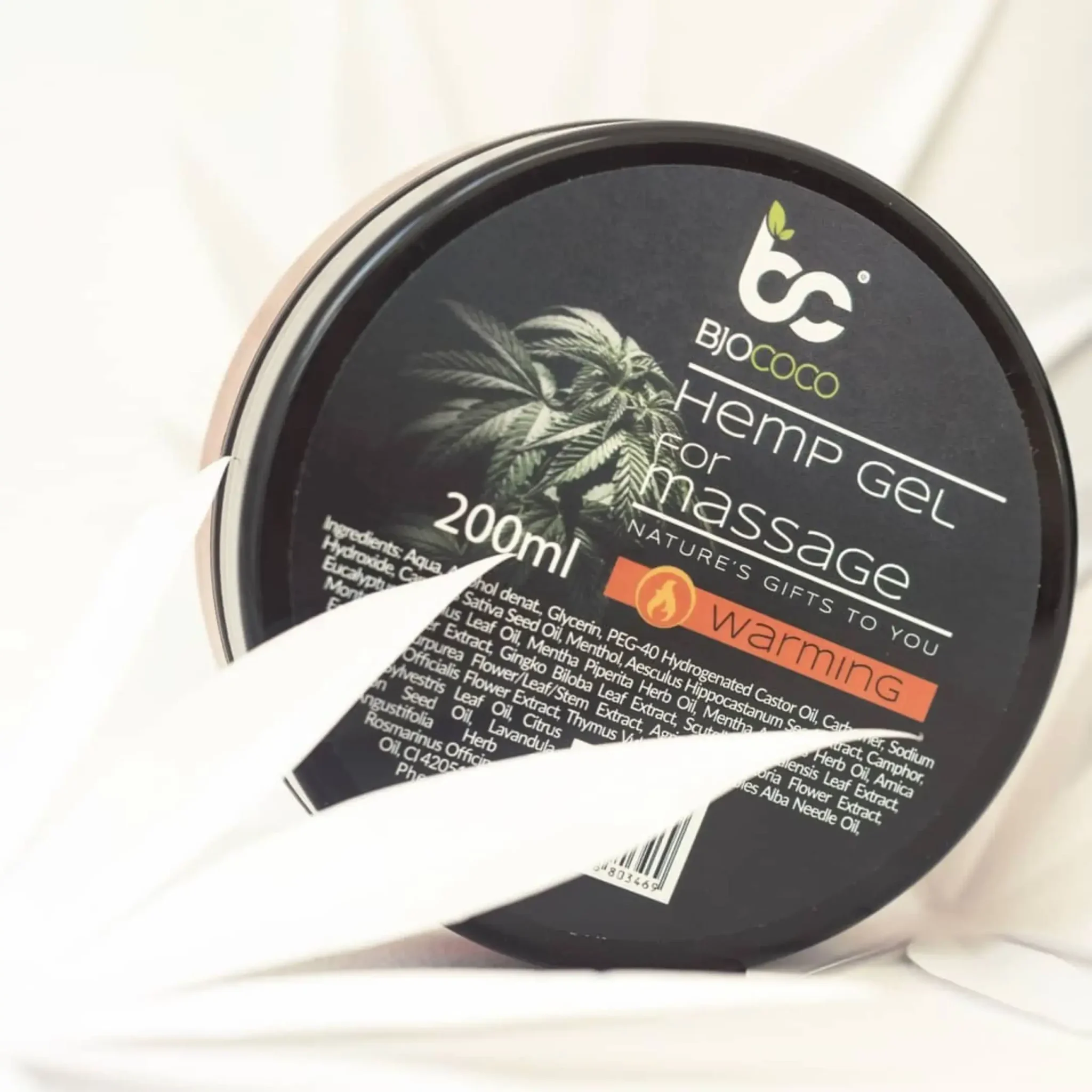 Zdjęcie opakowania rozgrzewającego żelu konopnego BjoCoco z elementami dekoracyjnymi w kształcie liści konopi na jasnym tle.
