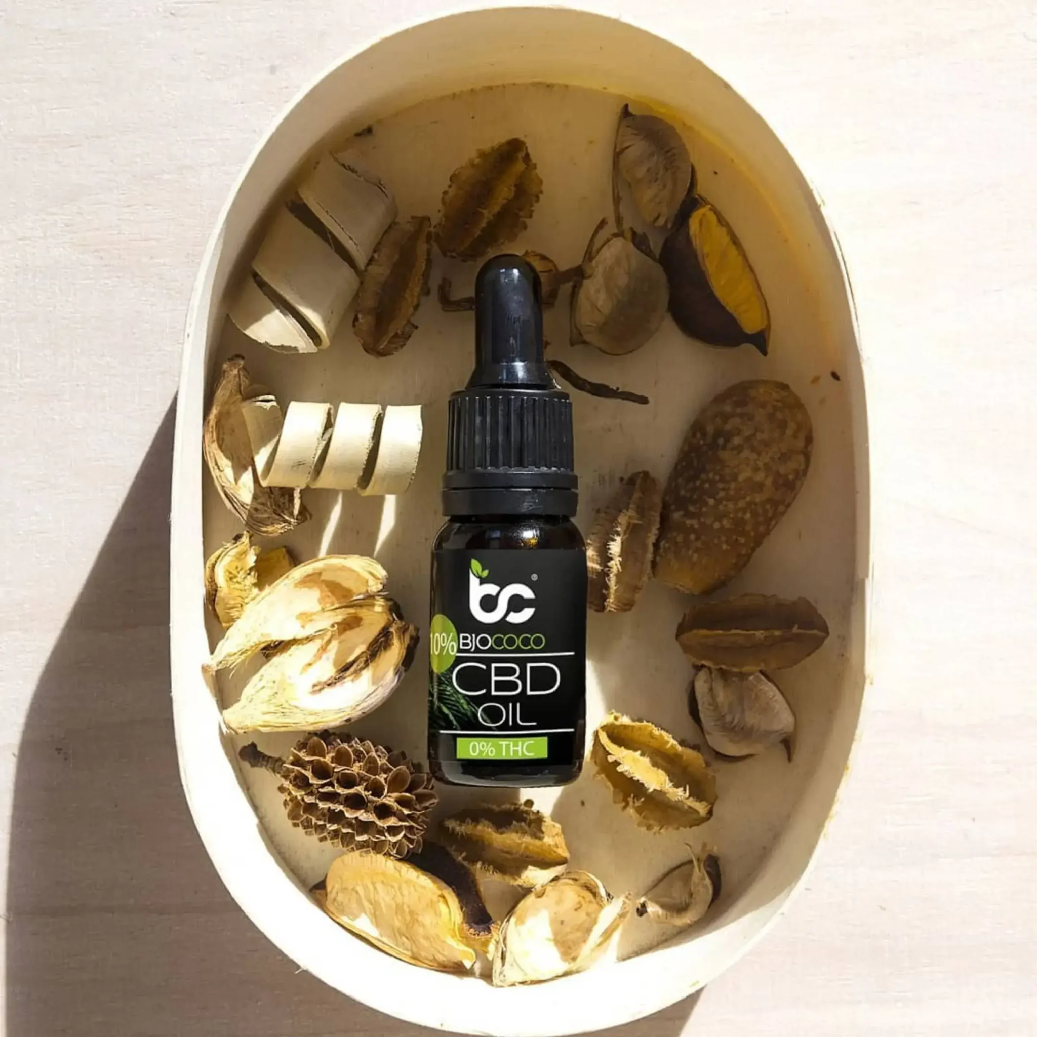 Butelka olejku CBD marki BjoCoco w dekoracyjnej misie z naturalnymi, suszonymi roślinami, idealny dla miłośników natury i ekologicznych rozwiązań.